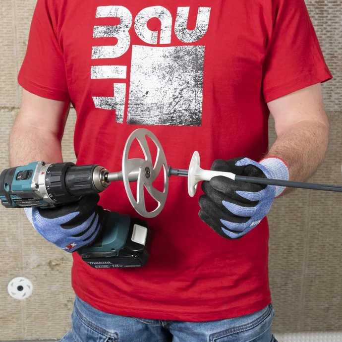 Heimwerker rüstet eine Bohrmaschine mit einem Rührquirl für Bauprojekte aus.