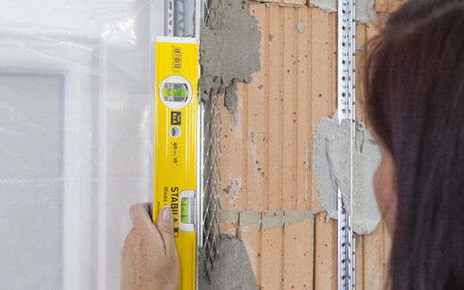 Überprüfung der lotgerechten Position der Metallwinkel (Eckschiene) mit der Wasserwaage.