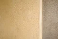 Glatte, verputzte Wand mit Farbverlauf von Beige nach Grau, ideal für moderne Innen- oder Außenbereiche.