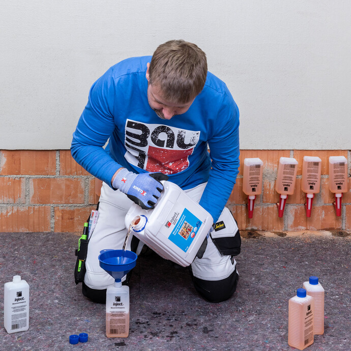 Der Handwerker füllt die einzelnen Fläschchen der Mauerwerkssperre wieder auf.