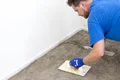 Heimwerker glättet neue Bodenfläche mit Baumit-Spachtel in einem Renovierungsprojekt.