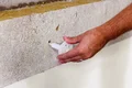 Person montiert Dämmstoffdübel in eine Wand, um Dämmmaterial zu befestigen. Perfekt für DIY-Renovierungsprojekte.