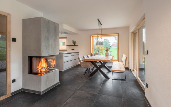 Wohnzimmer in modernem Design mit Kamin in Betonoptik, Granitboden und moderner Einrichtung mit wohngesundem, feinem, brillantweißem Strukturputz InStyle Edelweiß.