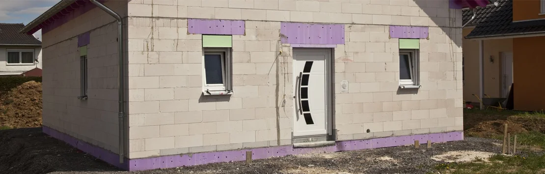Halb fertige Hausfassade mit W&auml;rmed&auml;mmung; zeigt ein Beispiel f&uuml;r effiziente Sanierung mit Baumit-Produkten.