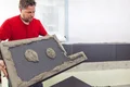 Mann beim Anbringen einer Wärmedämmplatte mit Klebemörtel an einer Hausfassade.