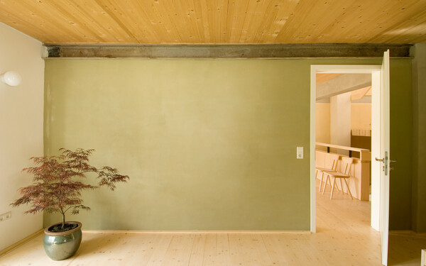 Heller Raum, der mit Lehmputz verarbeitet wurde. Mit einem eleganten Grünton versprüht der Raum eine besondere Leichtigkeit.