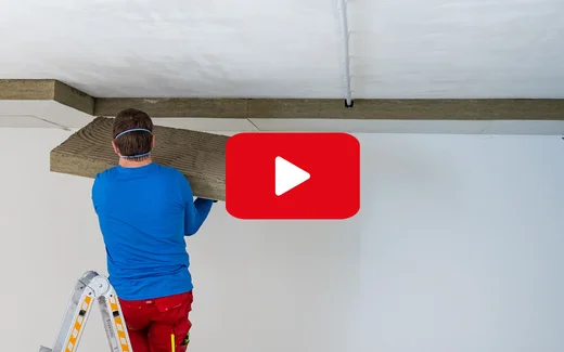 Heimwerker montiert Holzpaneele an der Decke; Anleitung für Deckenverkleidung auf Baumit selbst machen.