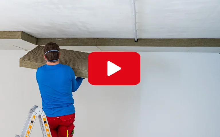 Heimwerker montiert Holzpaneele an der Decke; Anleitung für Deckenverkleidung auf Baumit selbst machen.