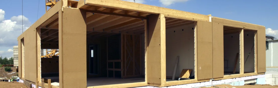 Holzrahmenbau w&auml;hrend der Bauphase mit sichtbarem Grundger&uuml;st und Dachkonstruktion auf einer Baustelle.