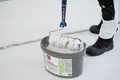 Detailfoto: verarbeitungsfertige Rollspachtel im Eimer und Walze zum Auftragen.