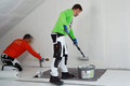 Der Airless- und Rollspachtel Silikat wird von einer Person mit der Walze aufgetragen und die andere Person glättet den Spachtel ab.