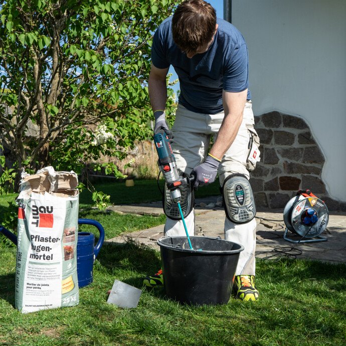 Pflasterfugenmörtel mit Wasser und elektrischem Rührwerk in einem Mörtelkübel anrühren.