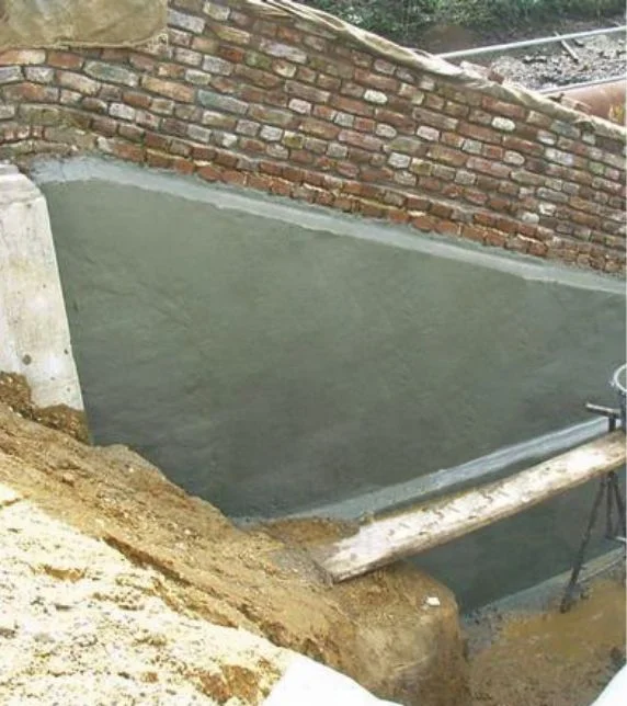 Stützmauer mit frischem Putzauftrag an schräger Backsteinwand im Außenbereich. Ideal für DIY-Renovierungsprojekte.