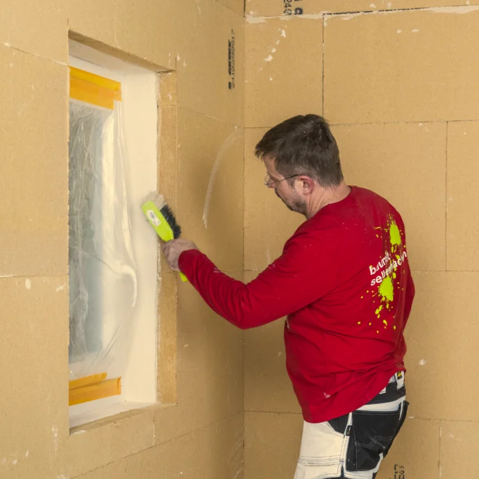 Heimwerker verputzt Wand mit Glättekelle; Schritt-für-Schritt-Anleitung zur Innenrenovierung mit Baumit-Produkten.