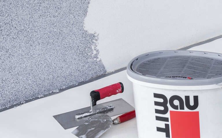 Baumit Mosaikputz mit Glättkelle und Maurerkelle im blauen Farbton: So verarbeitest du Buntsteinputz richtig mit dem richtigen Werkzeug