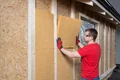 Die Holzfaser-Dämmplatte Thermoflex wird im Holzständerwerk positioniert.