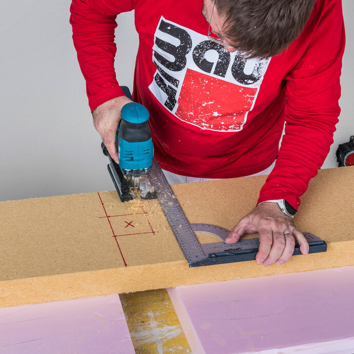Heimwerker schneidet Aussparung für Steckdose in Baumit Holzfaserdämmplatte mit Stichsäge und Winkel zu – Dämmplatte passgenau für Innendämmungsdose zuschneiden, Baumit Selbermachen Anleitung.