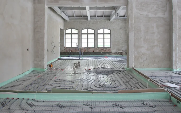 Renovierungsprojekt mit Fußbodenheizung in Bauphase, Sicht auf verlegte Heizschlangen auf Dämmmaterial in Rohbauumgebung.