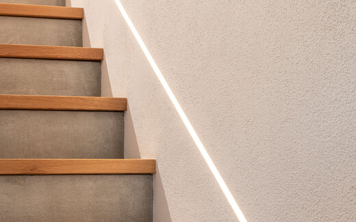Moderner Treppenaufgang mit Beton und Holz mit indirekter Beleuchtung und brillantweißem feinen InStyle Edelweiß.