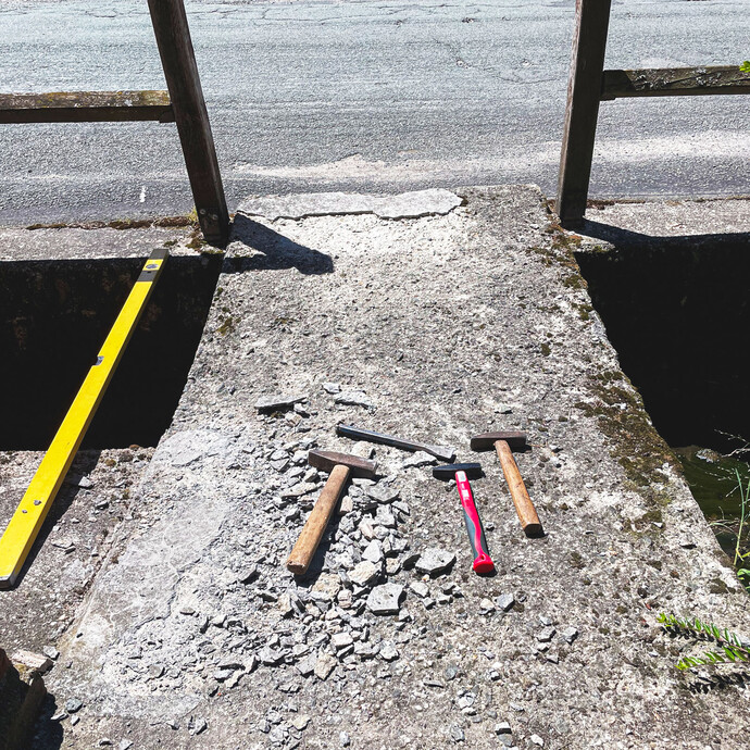 Lose und brüchige Teile sind auf dem Betonboden abgeschlagen. Hammer, Wasserwaage und weitere Werkzeuge werden dafür benötigt.