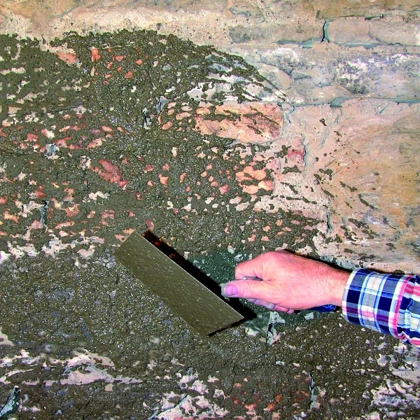 Hand verputzt eine raue Wand mit Spachtel und Mörtel für Heimwerkerprojekt.