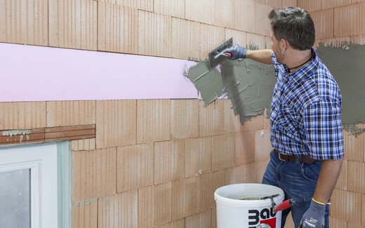 Heimwerker bringt den angemischten, frischen Putzmörtel bzw. Klebespachtel auf die XPS Platten auf.