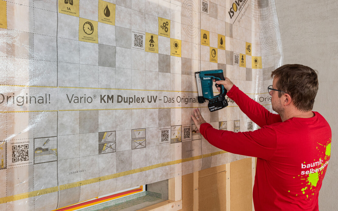 Baumit Handwerker &uuml;berspannt das Fenster mit der Dampfbremse ISOVER KM Duplex UV und tackert sie an der Tragkonstruktion der ersten D&auml;mmebene der Innend&auml;mmung fest. Anleitung zum Selbermachen.