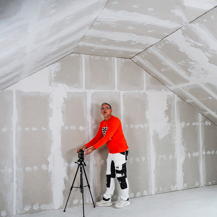 Der Heimwerker stellt den Kreuzlaser auf ein Stativ.