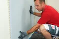 Mann verlegt Trockenbauwand mit Baumit Produkten, DIY-Anleitung für Heimwerker, Schritt für Schritt Renovierungstipps.