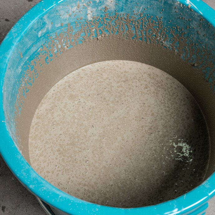 Nahaufnahme Foto: Blauer Eimer mit angerührter Ausgleichsmasse - Reifezeit beachten: Die Ausgleichsmasse bleibt ein paar Minuten stehen bis sie erneut durchgemischt wird.