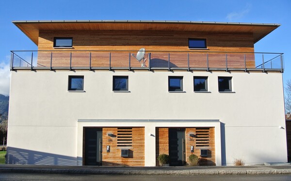 Putzfassade in Kombination mit Holzelementen für Obergeschoss und Eingangsbereich