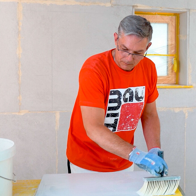Heimwerker trägt die Grundierung Mineralgrund auf den Kalziumsilikatplatte Anschlusskeil mit einem Malerquast auf.
