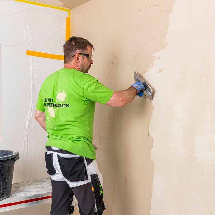 Heimwerker trägt Baumit Kalkin Kalkspachtel multifine mit der Glättkelle als Decklage auf die Innenwand auf – Deckspachtelung gleichmäßig verteilen, Baumit Selbermachen Anleitung.