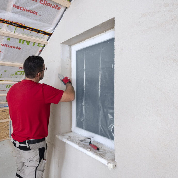 frischen Kalkputz mit Glättkelle und Maurerkelle in der Fensterlaibung auftragen