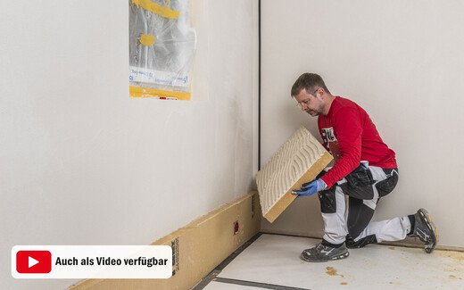 Heimwerker klebt die Holzfaserdämmplatte an die Wand. Innendämmung selber an die Wand kleben. Baumit DIY-Anleitung.
