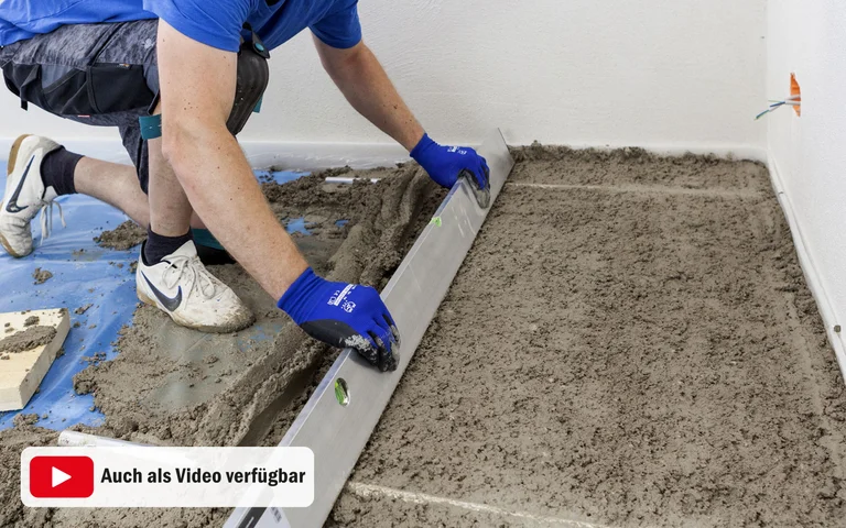 Heimwerker glättet Betonboden mit einer Abziehlatte für ein gleichmäßiges Ergebnis beim Estrich-Gießen.