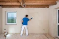 Heimwerker glättet Innenwand mit Spachtelmasse für ein gleichmäßiges Finish in renoviertem Raum.