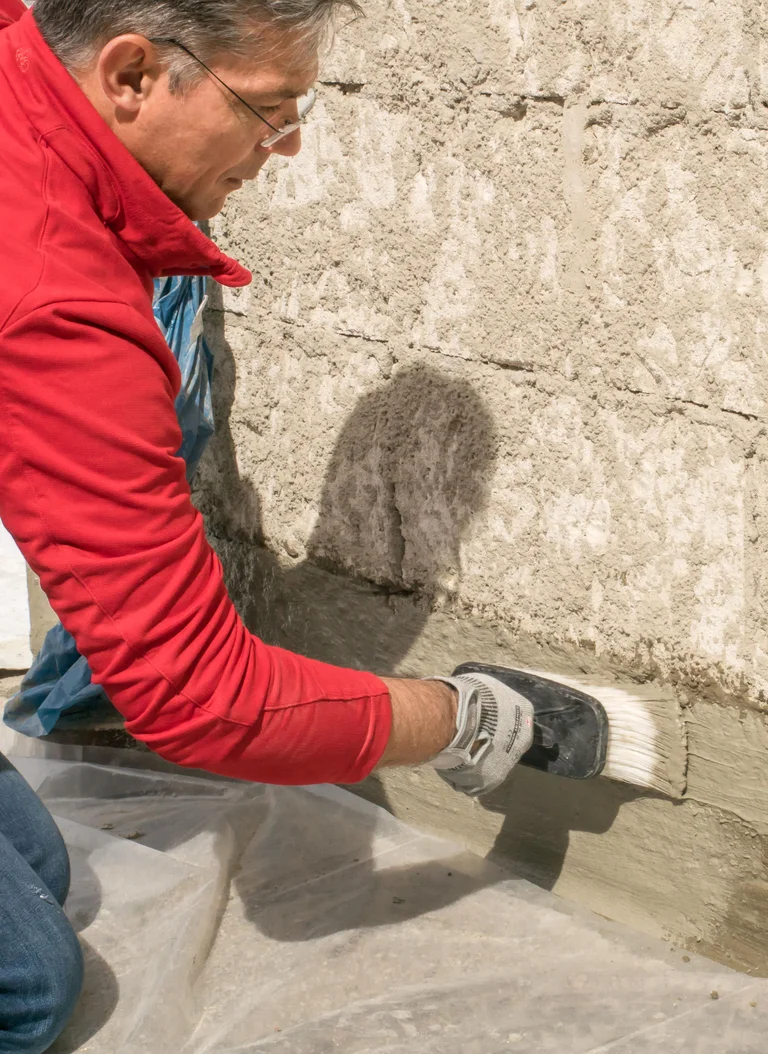Mann trägt Putz auf Außenwand auf, ideal für Heimwerker-Projekte zur Fassadensanierung mit Baumit-Baustoffen.