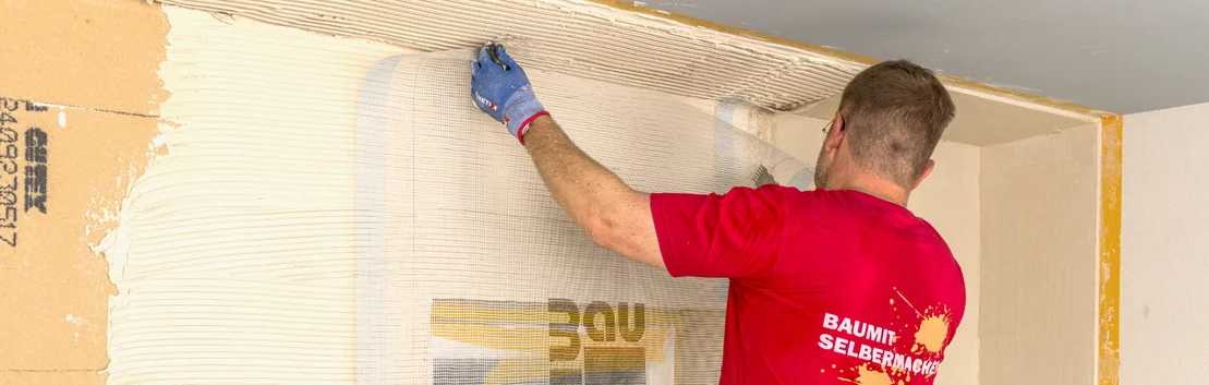 Handwerker tr&auml;gt in Heimwerkerprojekt Kleber auf Wand auf, bereitet Fl&auml;che f&uuml;r D&auml;mmung vor. Baumit DIY-Anleitung zur Renovierung.