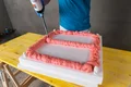 Person füllt Rahmen mit Montageschaum auf Styropor-Untergrund.