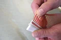 Nahaufnahme von Händen, die ein Armierungsgewebe für Fassadenanwendungen sorgfältig anbringen.