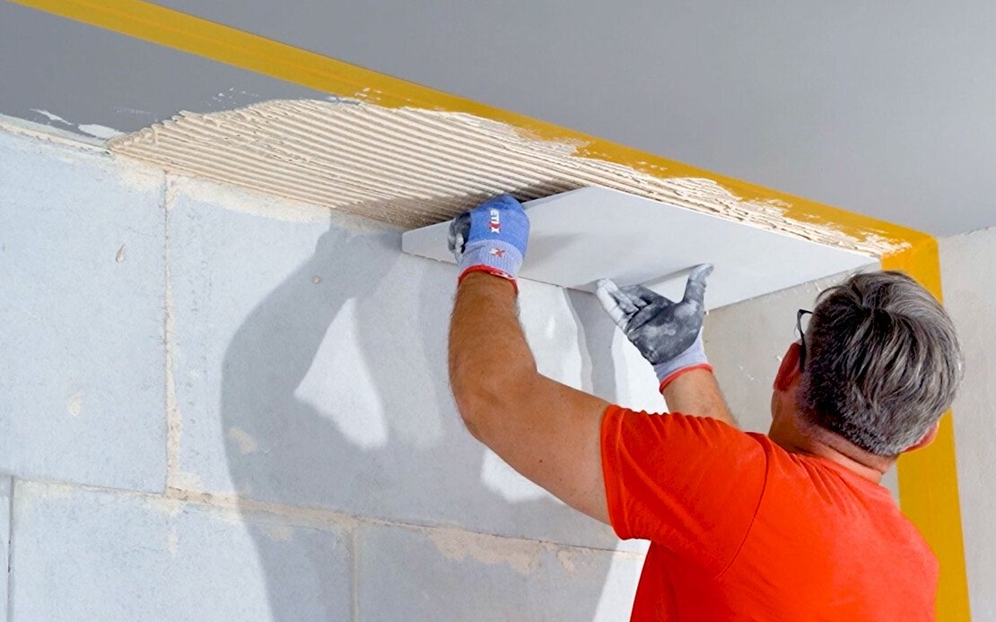 Heimwerker klebt den Kalziumsilikatplatte Anschlusskeil an die Decke.