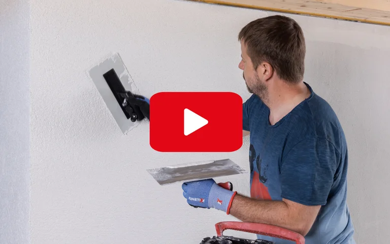 Mann trägt Putz auf Innenwand auf, Schritt-für-Schritt-Anleitung für Heimwerkerprojekte mit Baumit-Produkten.