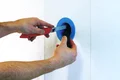 Heimwerker schneidet Kabeldurchführung in Trockenbauwand ein.