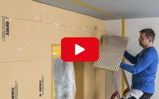 Mann bringt Dämmplatte an Wand an, Anleitung für Heimwerker auf Baumit Selbermachen.