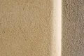 Oberfläche einer sandfarbenen Innenwand mit Strukturputz, ideal für Heimwerkerprojekte mit Baumit-Produkten.