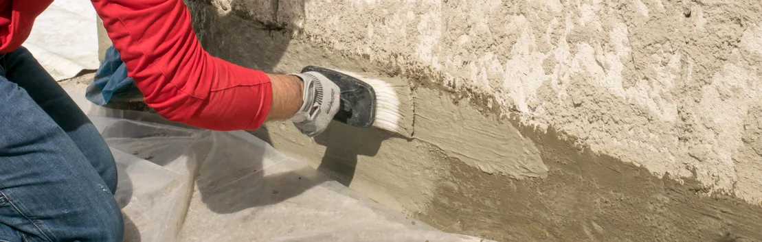 Person tr&auml;gt mit Pinsel Putz auf eine Wand auf, unter Verwendung von Baumit-Produkten f&uuml;r effiziente Heimwerkerprojekte.