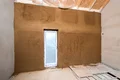 Renovierter Raum mit frischem Putz an der Wand, Holzboden und kleinem Fenster, ideal für Heimwerker-Projekte.