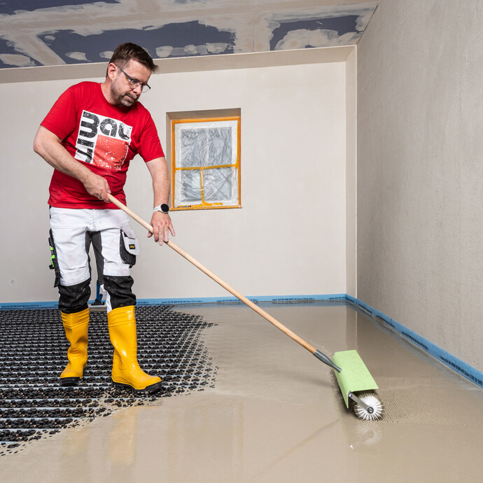 Heimwerker entlüftet die eingebaute Ausgleichsmasse mit Hilfe einer Stachelwalze (auch Igelwalze genannt).