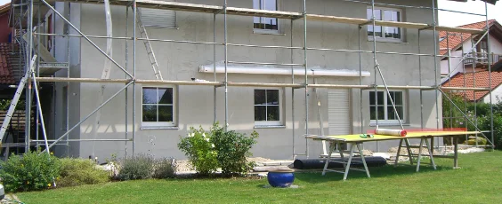 Hausfassade mit Baugerüst, bereit für Fassadenarbeiten; inspiriert zur DIY-Renovierung.